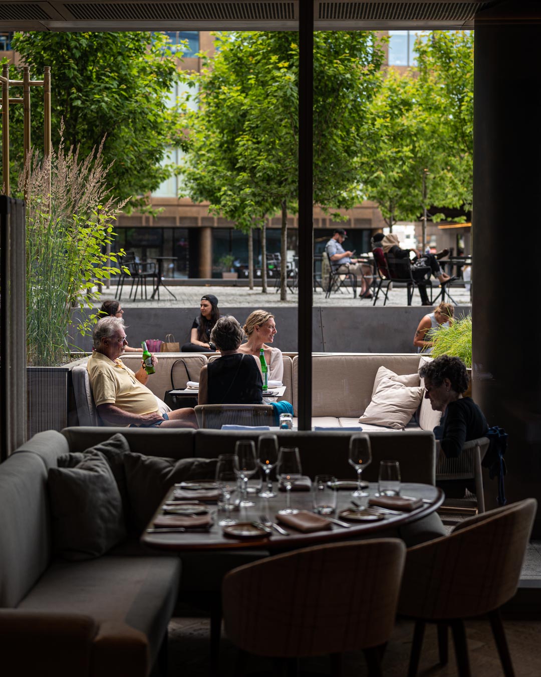 Interior shot looking outward at three guests sitting on patio at Drift Restaurant Halifax